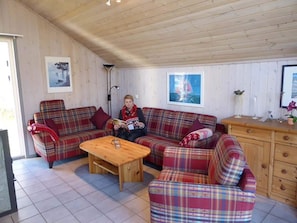 Ein gemütliches Wohnzimmer mit einem karierten Sofasessel, einem Holztisch und einer Kommode mit Schubladen.