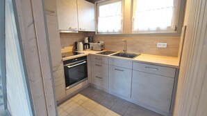 Cozinha compacta com forno embutido, pia e janela sobre a bancada.
