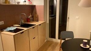 Une cuisine compacte comprenant un évier, un plan de travail et un coin repas avec une table et une chaise.