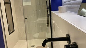 Une salle de bain moderne avec une douche à parois de verre, des toilettes et un lavabo doté d’un robinet noir.