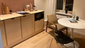 Una cocina compacta con encimera de madera, horno integrado y zona de comedor con mesa redonda y dos sillas.