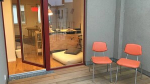 A modern interior with a glass door leading to a living area, two orange chairs, and a wooden floor. - Arbio I Lax Attic Studio in Lindenau (Leipzig)