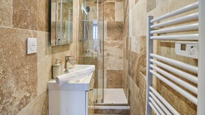 A modern bathroom with a glass-enclosed shower, a white sink, and a towel rack. - Charming Studio Center of Paris Le Marais (Paris)