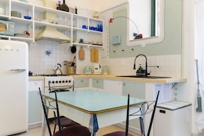 A kitchen with a stove, sink, and dining table with chairs.
