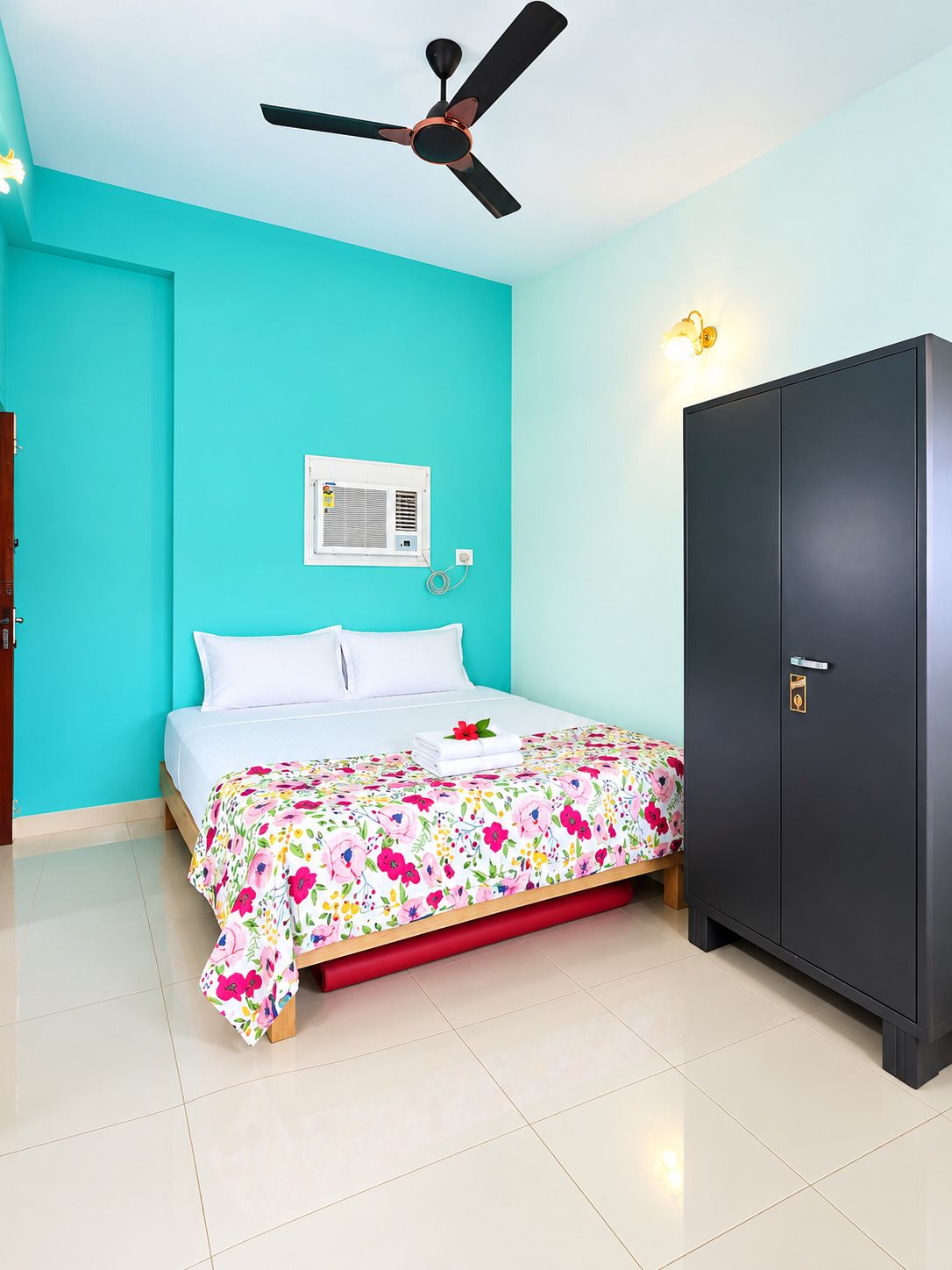 A bedroom with a bed, a ceiling fan, a wardrobe, and a wall-mounted air conditioner.