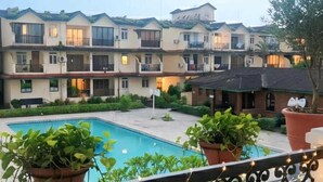 Un balcon donnant sur une piscine et sur un immeuble à plusieurs étages en arrière-plan.