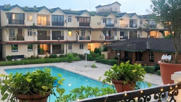 A balcony with a view of a swimming pool and a multi-story building in the background. - shradha luxury room (Calangute)