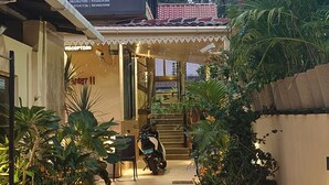 Une maison d’hôtes avec un espace d’accueil, des plantes en pot et une moto garée à l’extérieur.