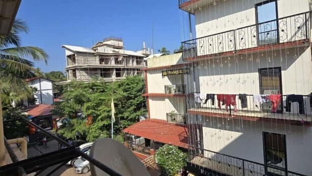 A multi-story building with balconies, a satellite dish, and a sign reading "TRANQUIL HILL." - shradha luxury room (Calangute)