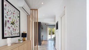 Un couloir avec une console en bois, une estampe botanique encadrée et une lampe noire.