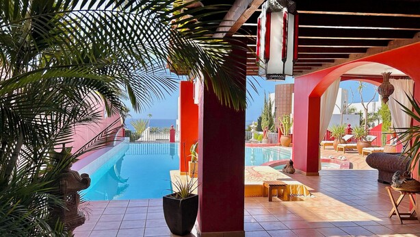 A pool area with a view of the sea, surrounded by red walls and tiled flooring. - RED-HOUSE, Red-House Tenerife Sur (Costa Adeje)