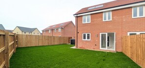 A residential area with a well-maintained lawn and a brick house with a sliding glass door. - Cotswold Green - Sleeps 5 - Free EV Charge (Tewkesbury)