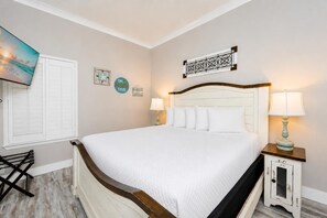 A bedroom with a large bed, a nightstand with a lamp, a wall clock, and a framed picture. - Phoenix X 102 1 Bedroom Condo (Orange Beach)
