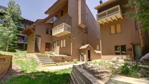 A multi-story building with a wooden exterior, a balcony on the second floor, and a staircase leading to the entrance.