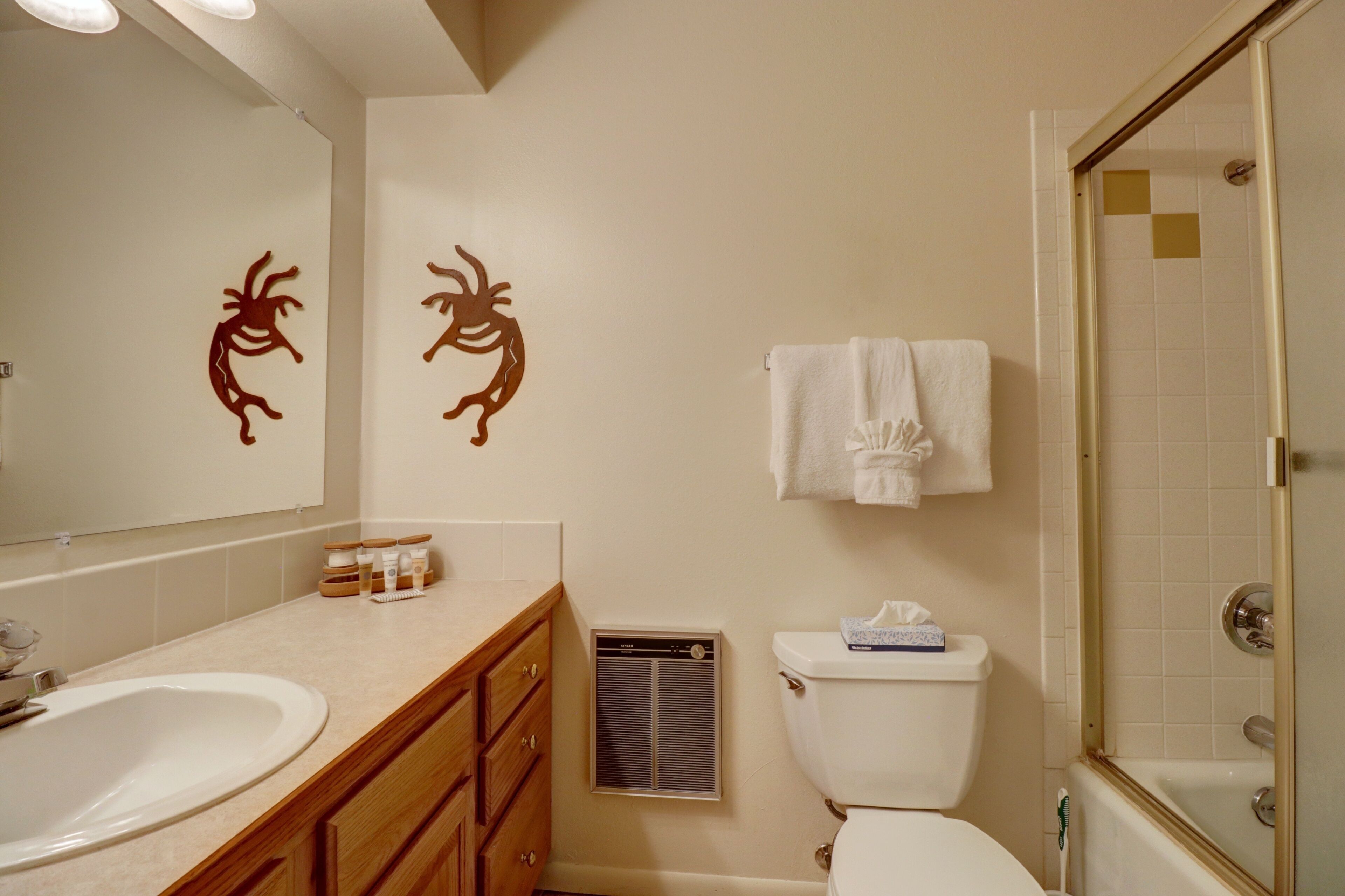 A bathroom with a sink, toilet, and shower. There are decorative wall stickers and a towel rack.