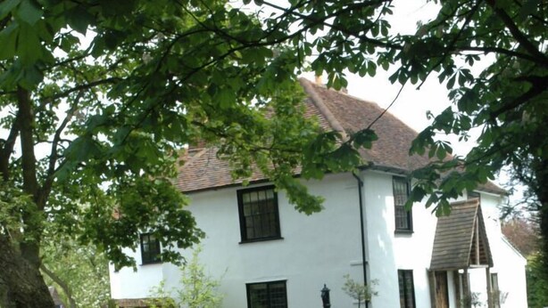 Una casa bianca con un cartello su una recinzione che recita 'The White House'.