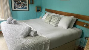 A neatly made bed with a white bedspread and pillows, a wooden headboard, and a bedside table with a lamp. - White house (Bishop's Stortford)