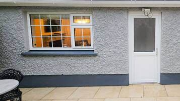 A building with a textured exterior, a white door, and a window with a view of the interior.