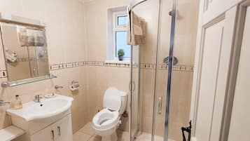 A bathroom with a toilet, sink, and shower.