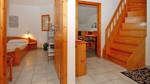 A bedroom with a wooden bed, a bedside table, and a nightstand. There is a mirror on the wall and a framed picture above the bed. A wooden staircase leads to another room. - Apartment in Wenkendorf for 7 Personen (Fehmarn)