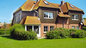 A two-story house with a sloped roof, a visible chimney, and a small porch with a white railing. - Apartment in Wenkendorf for 7 Personen (Fehmarn)
