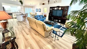 Una sala moderna con un sofá color beige, un sillón azul y un mueble para televisión.