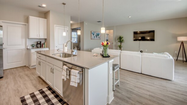 A modern kitchen with white cabinetry, a central island with a sink, and a dining area with a white sofa. - Welcome to Villa Liliana, Special Pricing, Modern private House, Heated Pool, (Cape Coral)