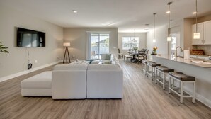 A modern living room with a sectional sofa, a dining area with a table and chairs, and a kitchen with bar stools. - Welcome to Villa Liliana, Special Pricing, Modern private House, Heated Pool, (Cape Coral)