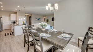A modern kitchen with white cabinets, a central island, and a dining area with a wooden table and chairs. - Welcome to Villa Liliana, Special Pricing, Modern private House, Heated Pool, (Cape Coral)