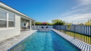 A rectangular swimming pool with a wooden deck, surrounded by a metal fence. - Welcome to Villa Liliana, Special Pricing, Modern private House, Heated Pool, (Cape Coral)
