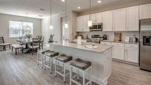 A modern kitchen with white cabinets, stainless steel appliances, and a central island with bar stools. - Welcome to Villa Liliana, Special Pricing, Modern private House, Heated Pool, (Cape Coral)
