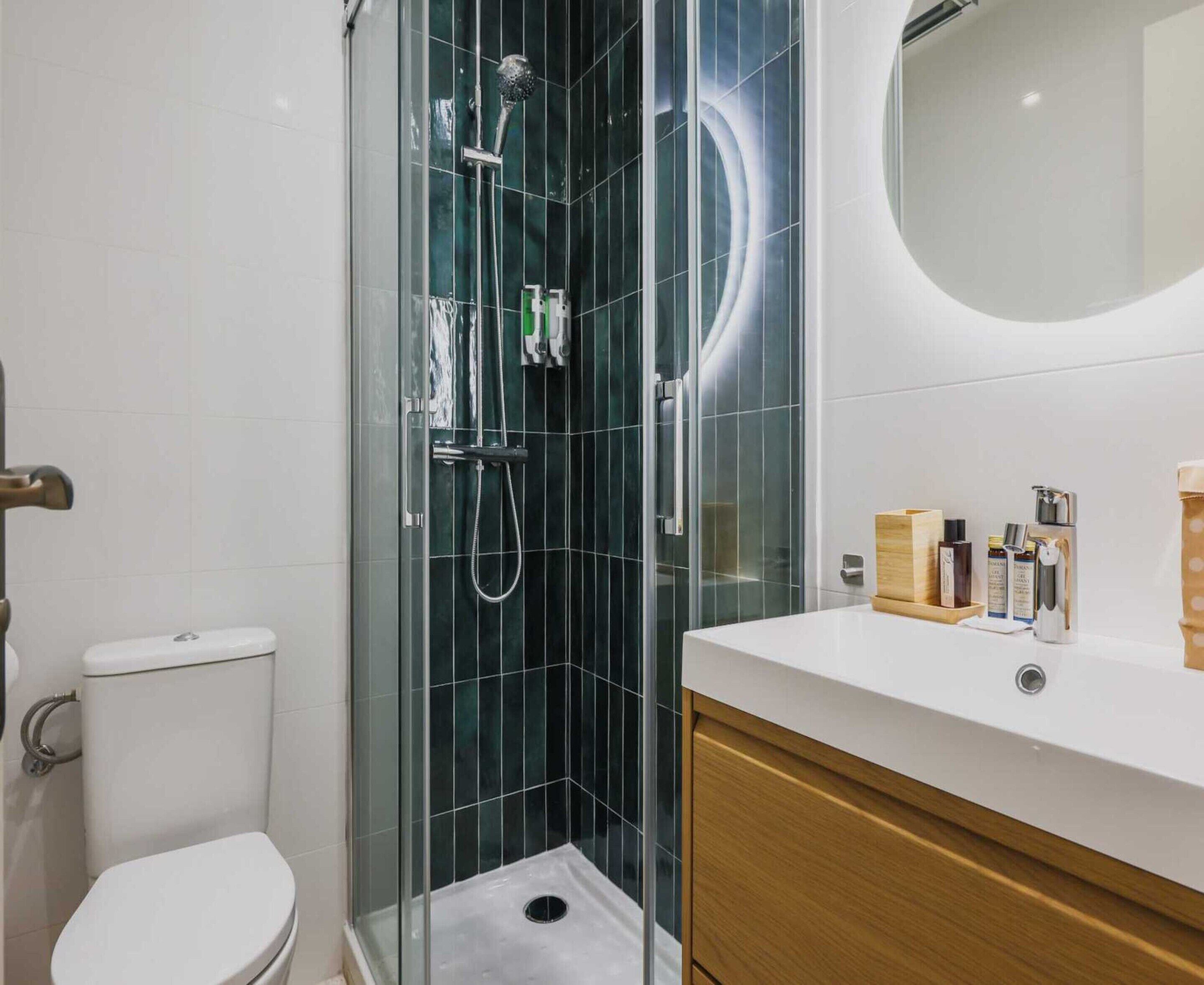 A modern bathroom with a glass-enclosed shower, a toilet, and a vanity with toiletries.