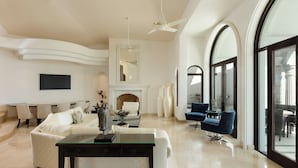 A modern living room with a fireplace, seating area, and large windows.