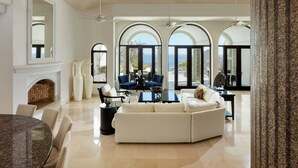 A spacious living room with a fireplace, a dining area with a round table, and a seating area with a sofa and chairs.