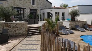 Ein Gebäude aus Stein mit Poolanlage, einschließlich Liegestühlen und einem kleinen Pool.