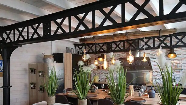 Ein Restaurant mit freiliegenden Backsteinwänden, Holzbalken und hängenden Pendelleuchten.