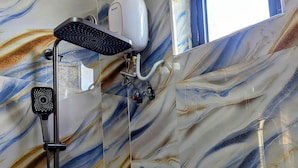 A bathroom with a shower, a handheld showerhead, and a handheld dryer. - twalumba resort and hotels (Lusaka)