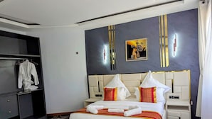 A hotel room with a bed, bedside tables, a wardrobe, and a desk with a coffee maker. - twalumba resort and hotels (Lusaka)