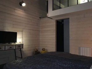 Una camera da letto con un letto, una TV su una cassettiera e una porta che dà su un'altra stanza.