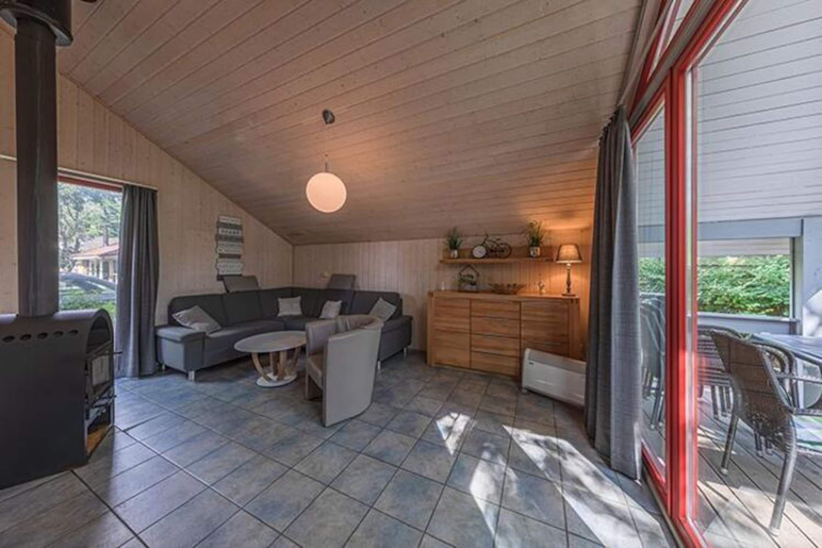 A cozy living room with a fireplace, sofa, coffee table, and a dining area with chairs.