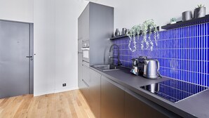 Una cucina moderna con un piano di lavoro grigio, un lavandino e uno schienale piastrellato blu.