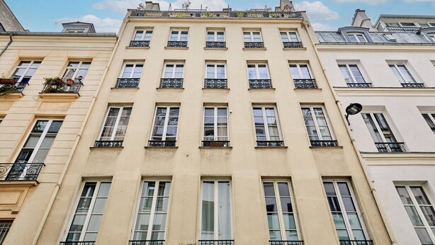Un edificio a più piani con facciata simmetrica, ampie finestre e ringhiere in ferro battuto decorate sui balconi.