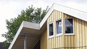 A two-story wooden house with a sloped roof, large windows, and a covered porch. - Skandinavisches Ferienhaus in Mirow (Mirow)