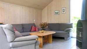 A cozy living room with two grey sofas, a wooden coffee table, and a fireplace. - Skandinavisches Ferienhaus in Mirow (Mirow)