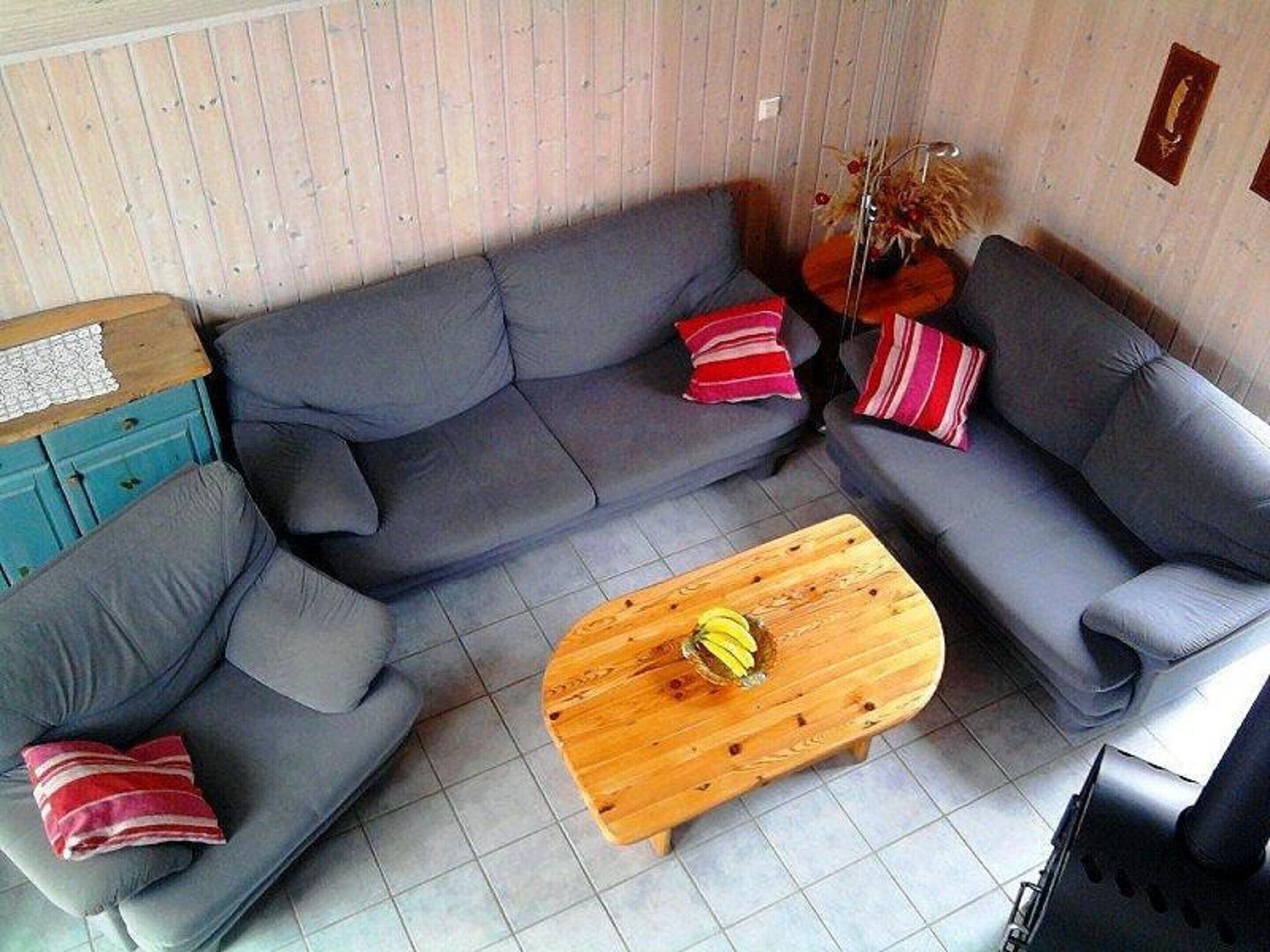 Een woonkamer met een grijze modulaire bank, een houten salontafel en een blauwe kast.