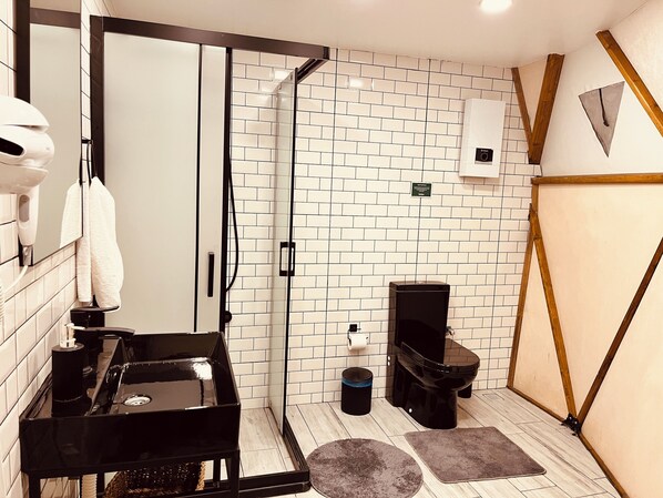 A modern bathroom with a glass shower enclosure, a black vanity, and a toilet. - Otelox Sinap Glamping - Dome (Erdemli)