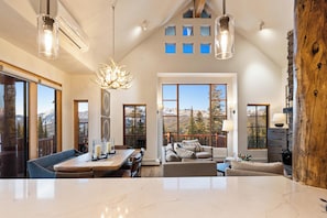 A spacious living area with a large window overlooking mountains, a dining area with a marble countertop, and a cozy seating area with a fireplace.