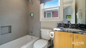 A bathroom with a bathtub, toilet, and vanity with a mirror.