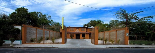A gated entrance to a building with a flat roof and a sign above the door. - Hotel El Cerro (Liberia)
