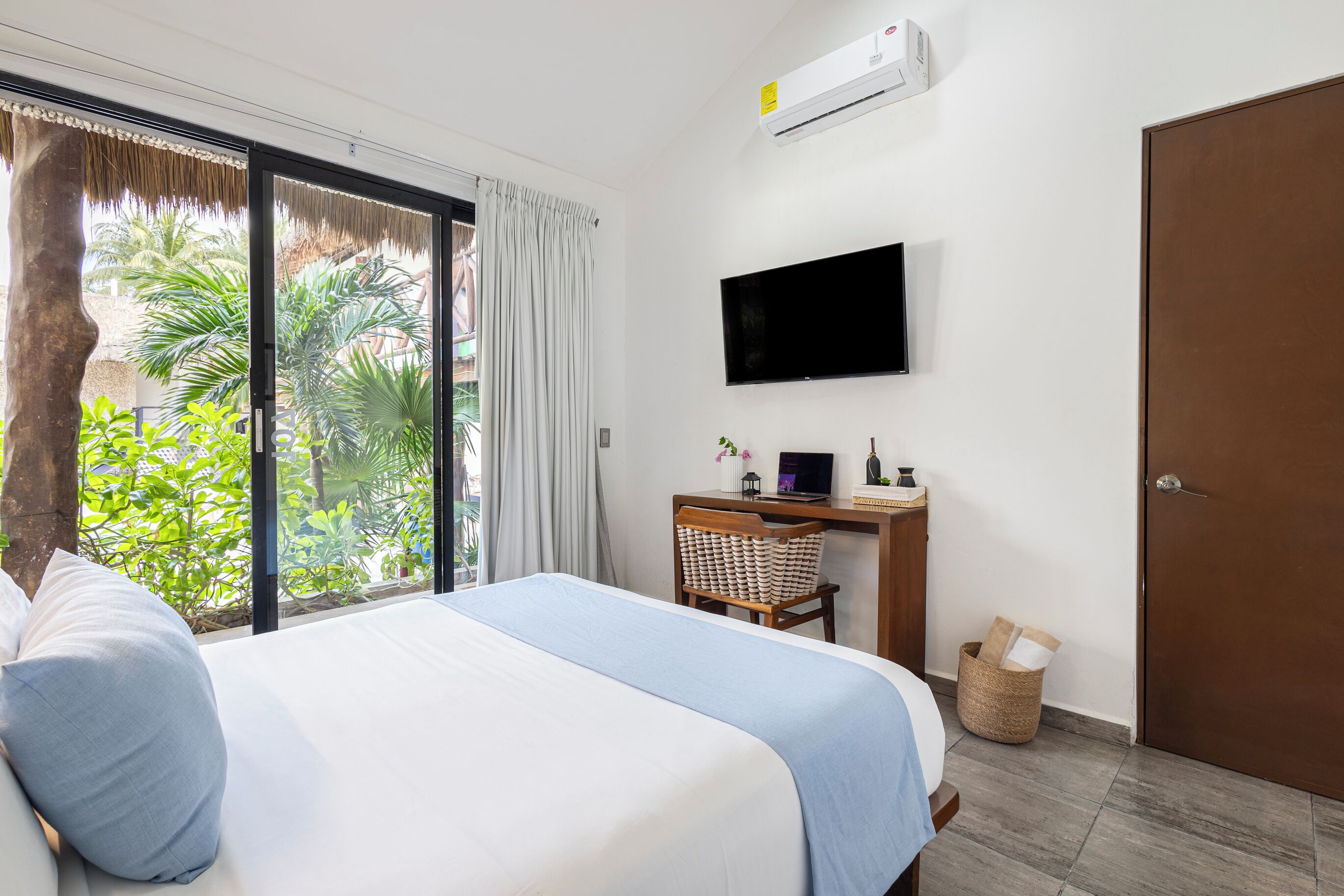 Une chambre d’hôtel avec un lit, un bureau avec un ordinateur, une télévision et une porte.